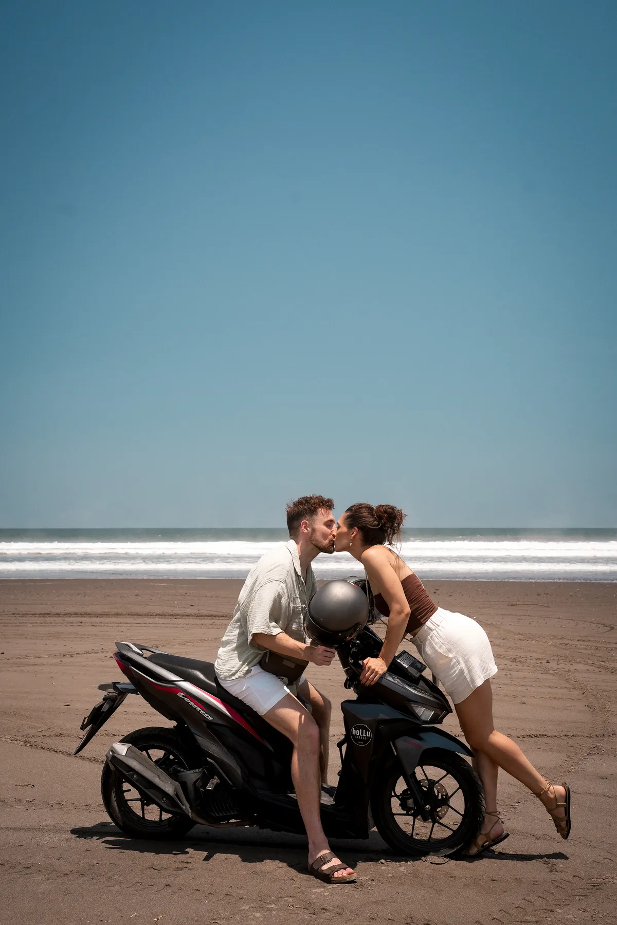 Wir küssen uns auf einem Roller an einem Strand auf Bali.